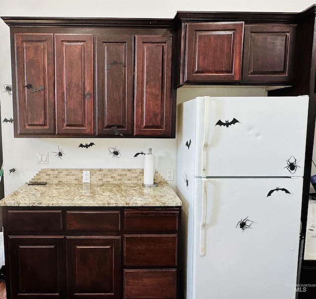 kitchen featuring dark brown cabinets and white fridge