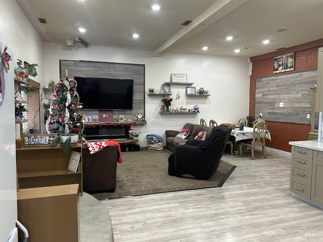 living room featuring beamed ceiling and light hardwood / wood-style floors