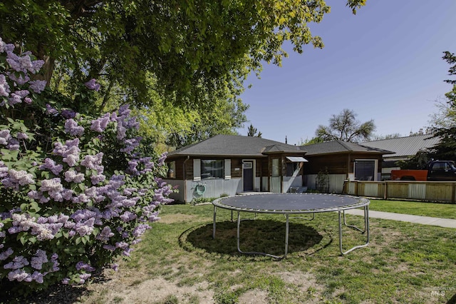 exterior space with a trampoline, fence, and a front yard
