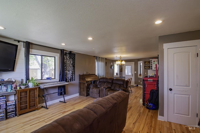 living room with baseboards, a notable chandelier, a wealth of natural light, and light wood-type flooring