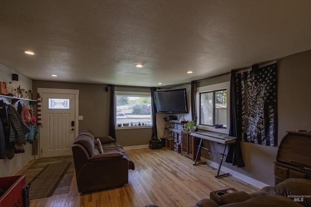 living area with baseboards, wood-type flooring, recessed lighting, and a textured ceiling