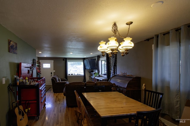 dining area featuring recessed lighting, a textured ceiling, wood finished floors, and a notable chandelier