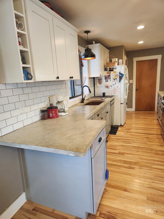 kitchen featuring white cabinets, a sink, recessed lighting, light wood-type flooring, and backsplash