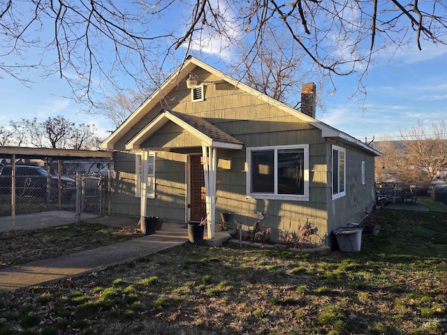 bungalow-style home with a shingled roof, a chimney, a gate, and fence