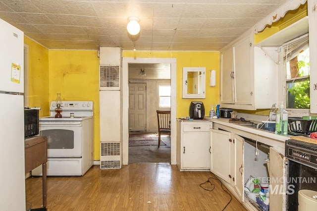 145 S 13th E, Mountain Home, ID 83647 - kitchen with white electric stove, white cabinets, light wood-style flooring, light countertops, and a heating unit