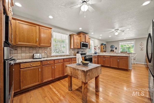 7425 Robinson Rd, Kuna, ID 83634 - kitchen with stainless steel appliances, ceiling fan, a peninsula, brown cabinets, and light wood-style flooring