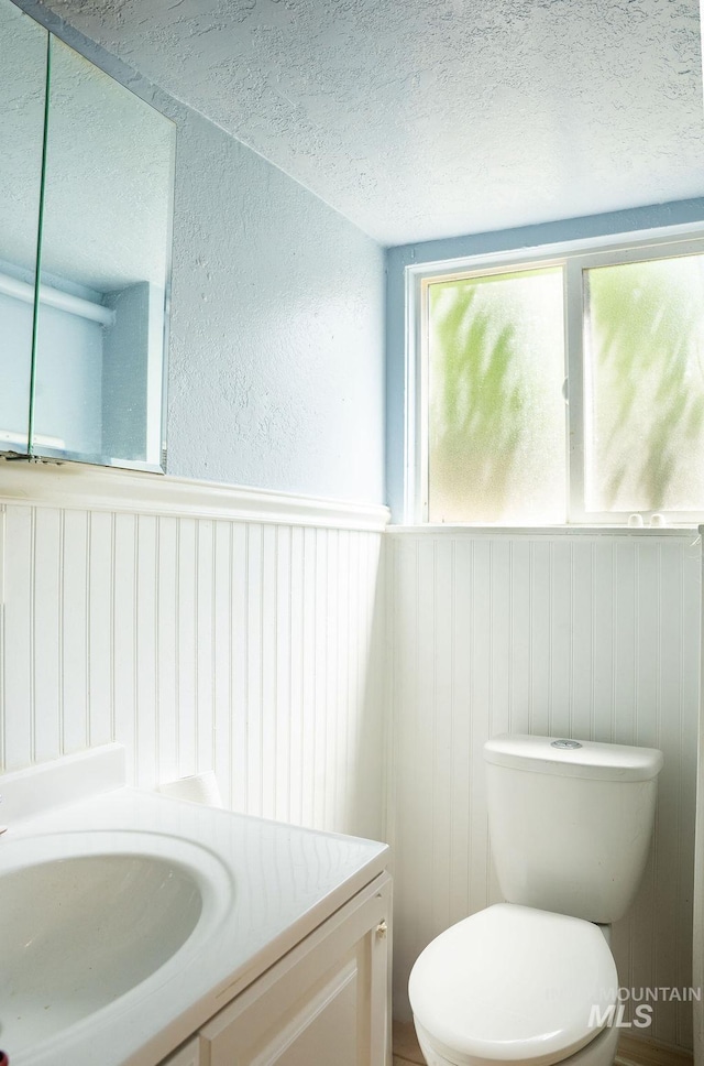304 6th Ave, Lewiston, ID 83501 - bathroom with a textured ceiling, vanity, toilet, a wainscoted wall, and a textured wall