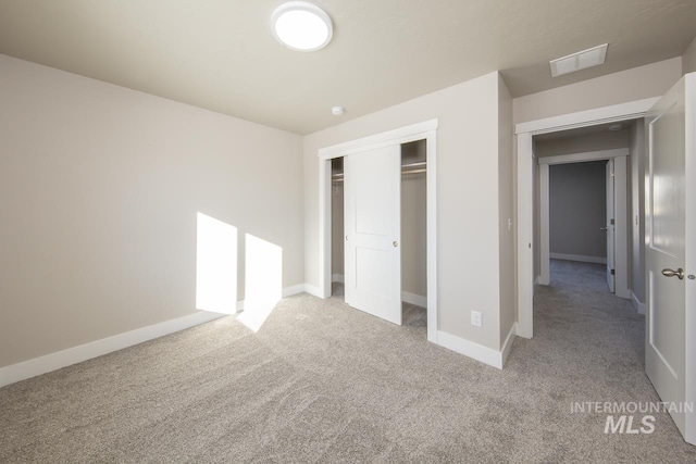 unfurnished bedroom featuring baseboards, visible vents, a closet, and light colored carpet