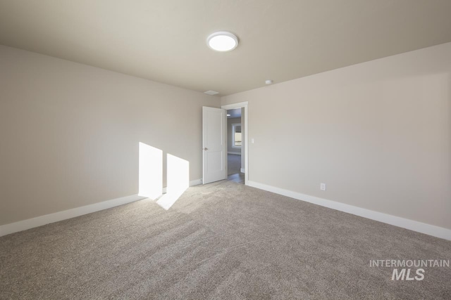 spare room featuring carpet and baseboards