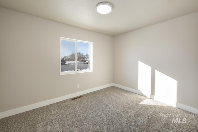 spare room with carpet, visible vents, and baseboards