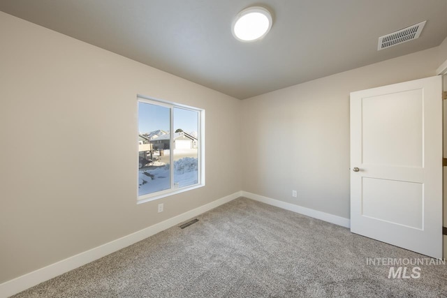 carpeted empty room featuring baseboards and visible vents