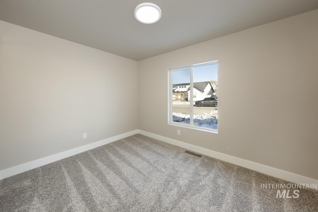 empty room featuring carpet floors, visible vents, and baseboards