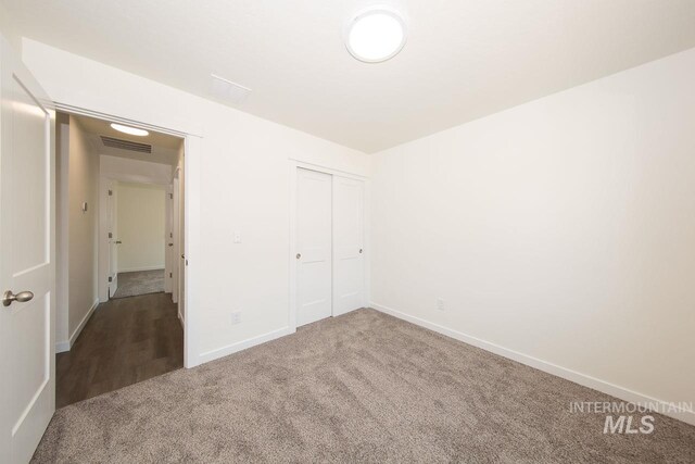 unfurnished bedroom featuring a closet, carpet, visible vents, and baseboards