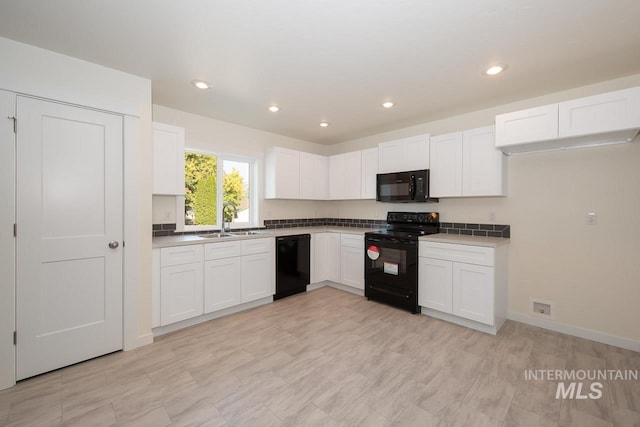 kitchen with baseboards, white cabinets, black appliances, a sink, and recessed lighting