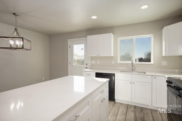 kitchen featuring white cabinets, light wood-style flooring, black appliances, a sink, and recessed lighting