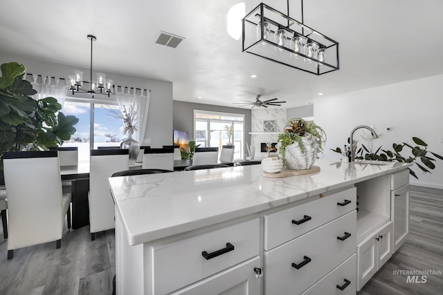 922 Victory Dr, Gooding, ID 83330 - kitchen with visible vents, ceiling fan with notable chandelier, wood finished floors, white cabinetry, and a sink