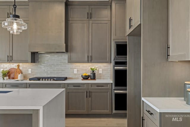 6920 N Spencer Way, Meridian, ID 83646 - kitchen featuring stainless steel appliances, decorative backsplash, light wood-type flooring, pendant lighting, and ventilation hood