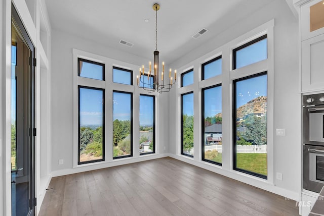 unfurnished dining area featuring hardwood / wood-style flooring and a chandelier