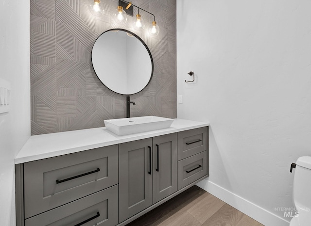 bathroom with toilet, vanity, and wood-type flooring