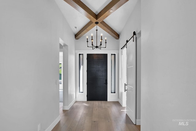 foyer entrance with an inviting chandelier, a barn door, hardwood / wood-style floors, and beamed ceiling