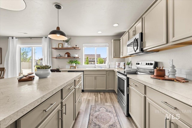 4447 W Everest St, Meridian, ID 83646 - kitchen with appliances with stainless steel finishes, pendant lighting, a healthy amount of sunlight, and light wood-type flooring