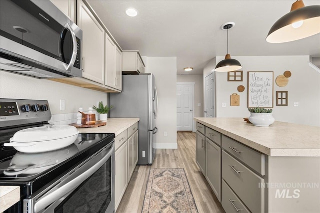 4447 W Everest St, Meridian, ID 83646 - kitchen with hanging light fixtures, light countertops, light wood-style flooring, stainless steel appliances, and gray cabinetry