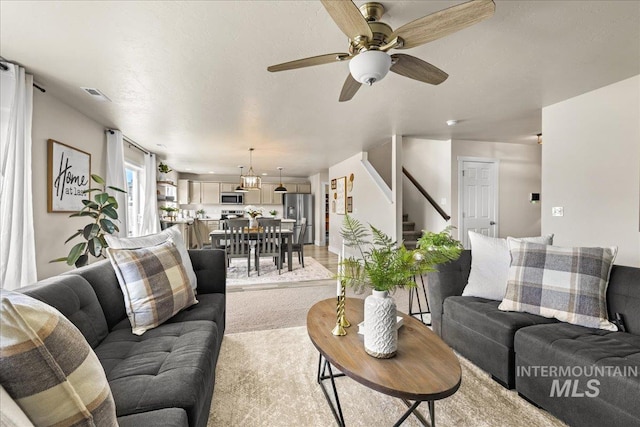 4447 W Everest St, Meridian, ID 83646 - living room with ceiling fan, visible vents, light carpet, and stairway