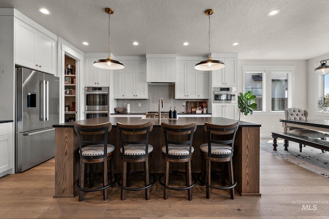 5209 W Strant Steet, Eagle, ID 83616 - kitchen featuring stainless steel appliances, dark countertops, recessed lighting, white cabinets, and tasteful backsplash