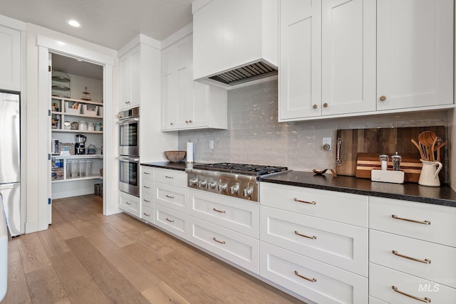 5209 W Strant Steet, Eagle, ID 83616 - kitchen with appliances with stainless steel finishes, white cabinetry, premium range hood, dark countertops, and light wood-style floors