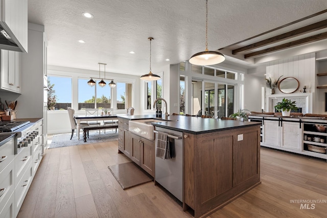 5209 W Strant Steet, Eagle, ID 83616 - kitchen featuring appliances with stainless steel finishes, a textured ceiling, dark countertops, light wood-type flooring, and a kitchen island with sink