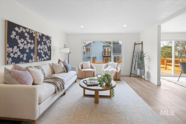 living room with a healthy amount of sunlight, a textured ceiling, and light wood-type flooring