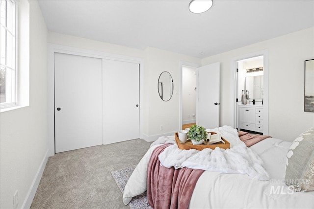 bedroom with ensuite bathroom, a closet, and light colored carpet