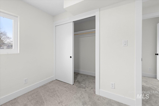 unfurnished bedroom with light colored carpet and a closet