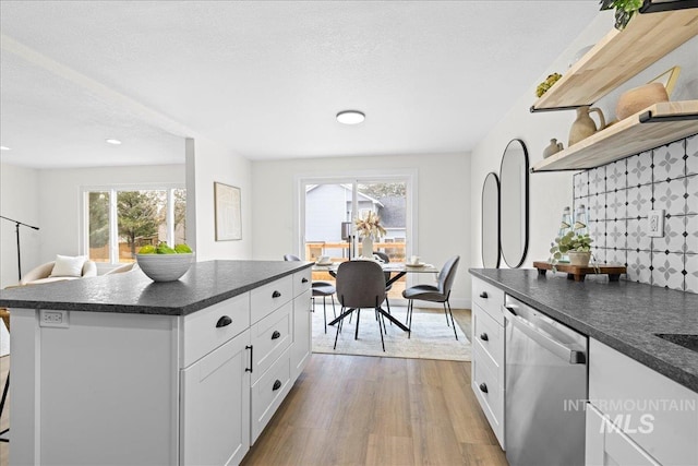 kitchen featuring light wood-type flooring, white cabinets, a textured ceiling, dishwasher, and a kitchen island