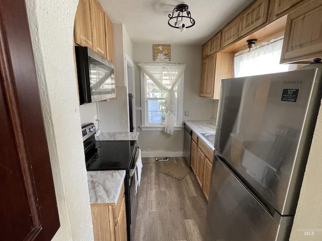 512 19th Ave S, Nampa, ID 83651 - kitchen featuring stainless steel appliances, light countertops, wood finished floors, a textured ceiling, and baseboards
