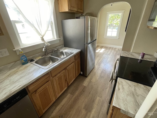 512 19th Ave S, Nampa, ID 83651 - kitchen with stainless steel appliances, a sink, light wood-type flooring, light countertops, and arched walkways