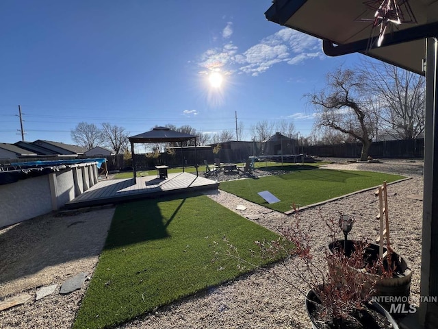 view of yard with a gazebo, a trampoline, a fenced backyard, and a deck