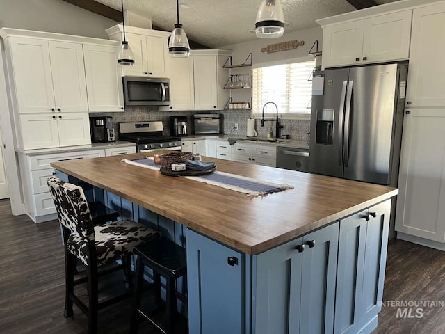 kitchen with butcher block countertops, backsplash, open shelves, and stainless steel appliances