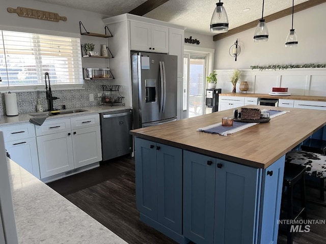 kitchen featuring open shelves, a textured ceiling, a sink, wood counters, and stainless steel appliances