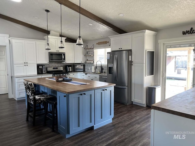 kitchen with a textured ceiling, wooden counters, decorative backsplash, stainless steel appliances, and dark wood-style flooring