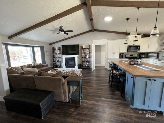 living room with a ceiling fan, a textured ceiling, vaulted ceiling with beams, dark wood finished floors, and baseboards