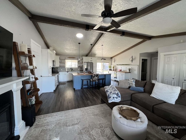 living room with lofted ceiling with beams, a ceiling fan, a textured ceiling, and dark wood-style floors