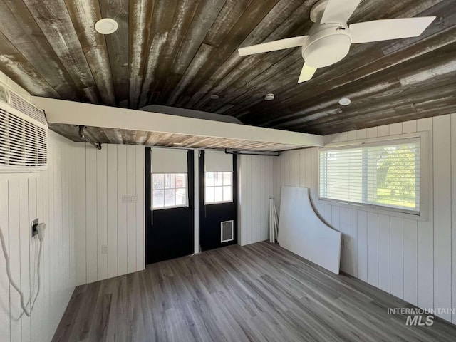 below grade area featuring wood finished floors, wood ceiling, ceiling fan, wood walls, and visible vents