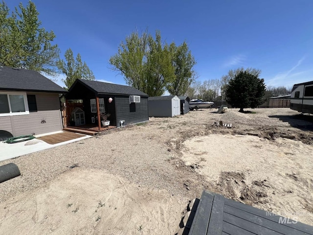 view of yard featuring a wooden deck, an outbuilding, and fence