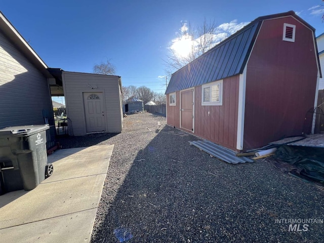 view of side of home with a storage unit, an outbuilding, a gambrel roof, and metal roof