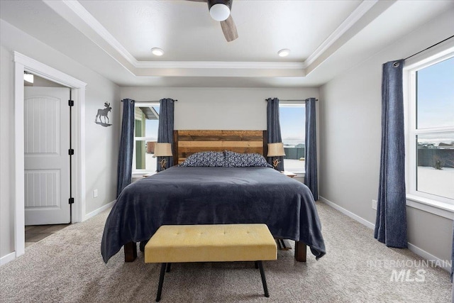 carpeted bedroom with a tray ceiling, baseboards, ceiling fan, and crown molding