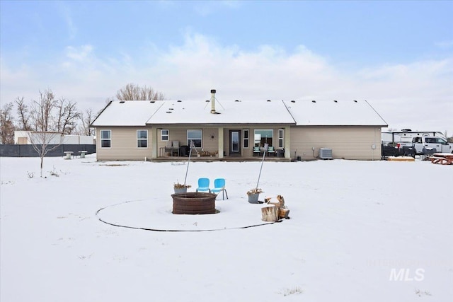 snow covered house featuring central AC unit and an outdoor fire pit