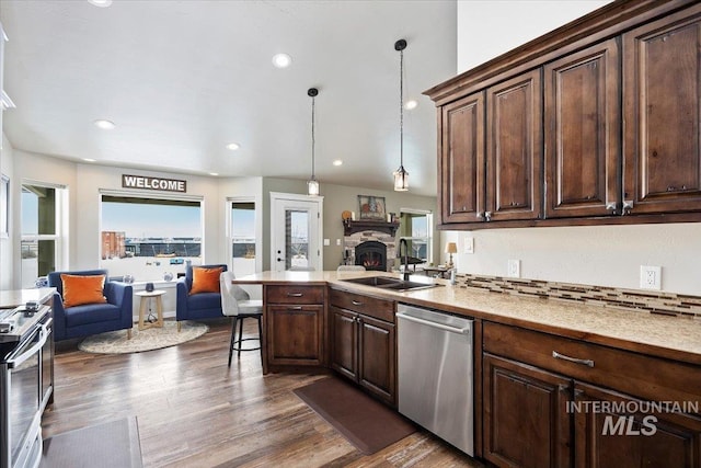 kitchen with dark wood-type flooring, a sink, open floor plan, appliances with stainless steel finishes, and dark brown cabinets