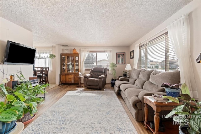 living area with light wood-style floors, visible vents, and a textured ceiling