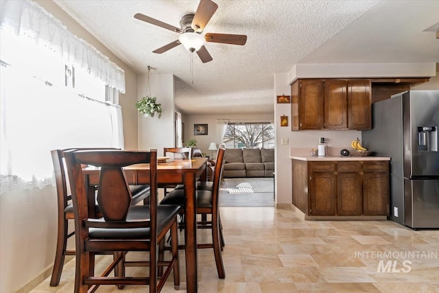 dining room with baseboards, a textured ceiling, and a ceiling fan